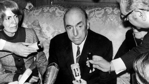 Pablo Neruda spricht am 21. Oktober 1971 in der chilenischen Botschaft in Paris in mehrere Mikrofone. Links neben ihm sitzt seine Frau Mathilde Urrutia.