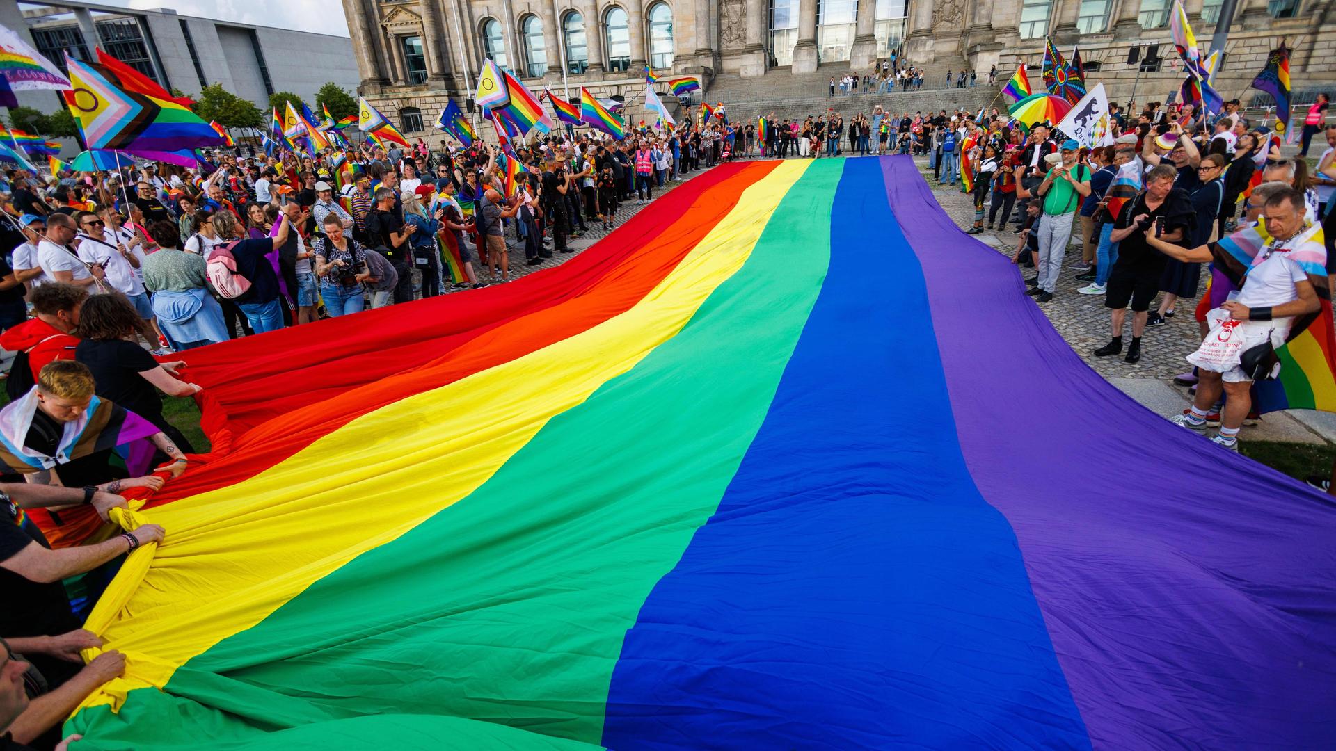 Teilnehmer einer Protestaktion rollen eine 400 Quadratmeter große Regenbogenflagge vor dem Reichstag aus. Teilnehmer einer Protestaktion rollen eine 400 Quadratmeter große Regenbogenflagge vor dem Reichstag aus.