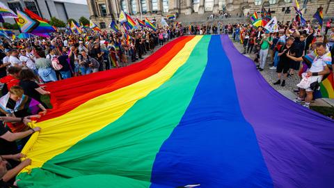 Teilnehmer einer Protestaktion rollen eine 400 Quadratmeter große Regenbogenflagge vor dem Reichstag aus.