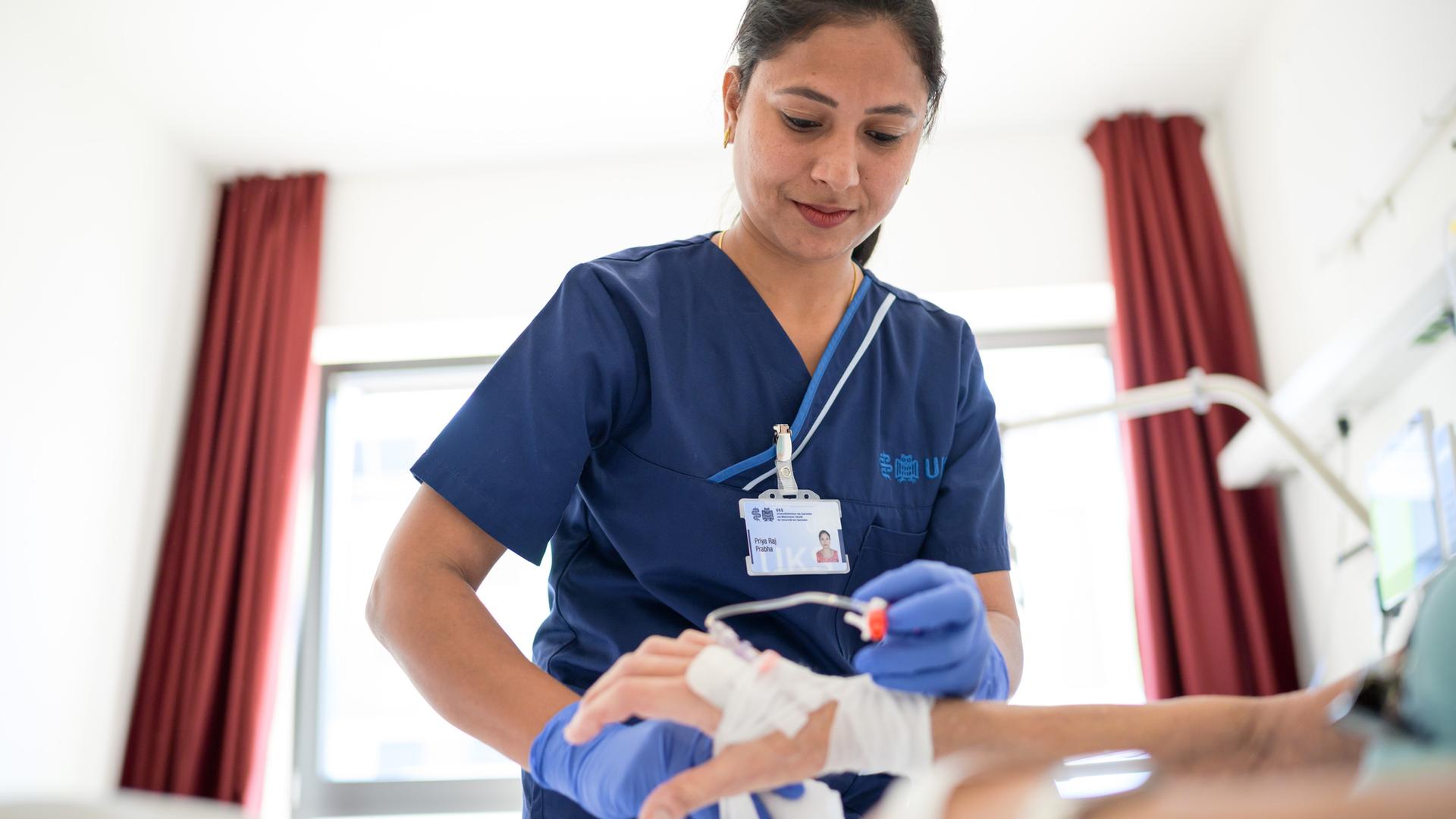 Eine indische Pflegekraft legt einer Patientin eine Infusion. Eine indische Pflegekraft legt einer Patientin eine Infusion.