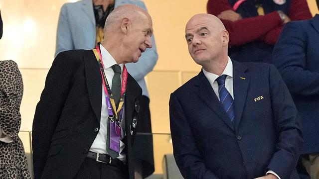 Bernd Neuendorf steht auf einer Stadiontribüne neben Gianni Infantino und spricht mit ihm.