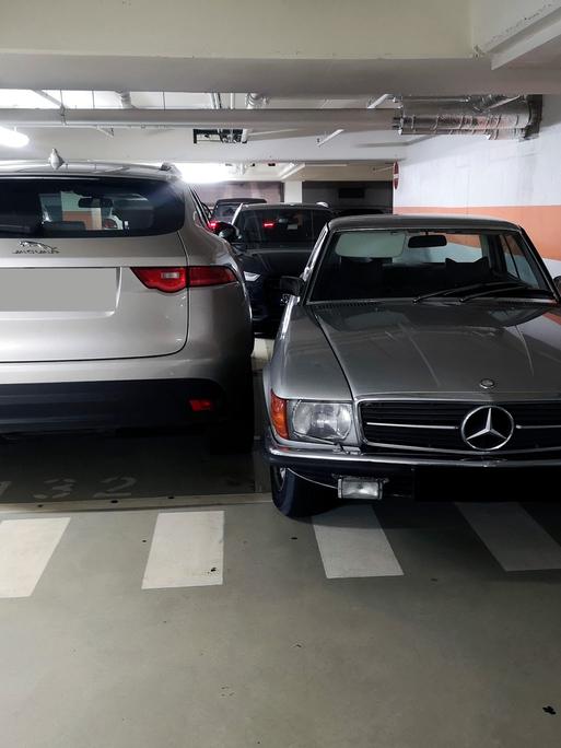 David gegen Goliath: Zwischen den Fahrzeugen verschiedener Generationen liegen Welten. Recht im Bild ein älterer Mercedes, links ein modernes SUV. 