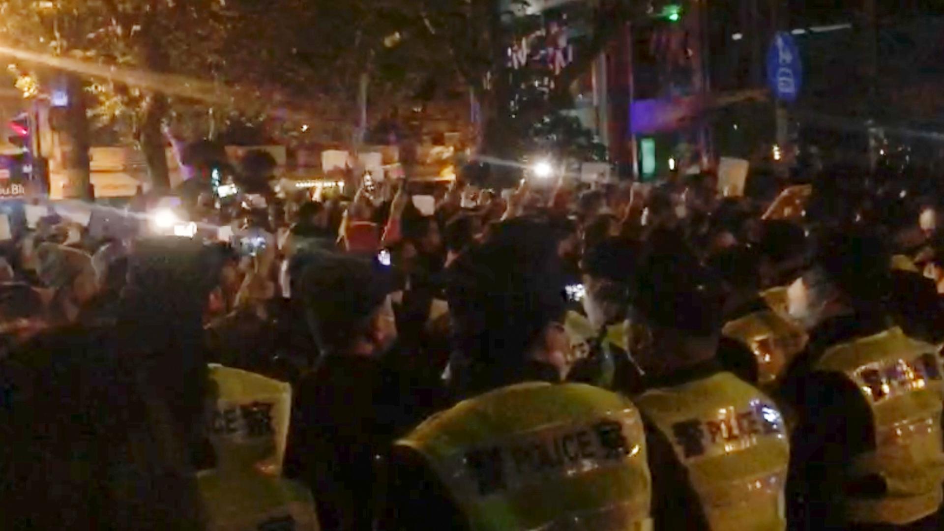 In diesem Bild aus einem Video beobachtet die Polizei (im Vordergrund) die Demonstranten in Shanghai.