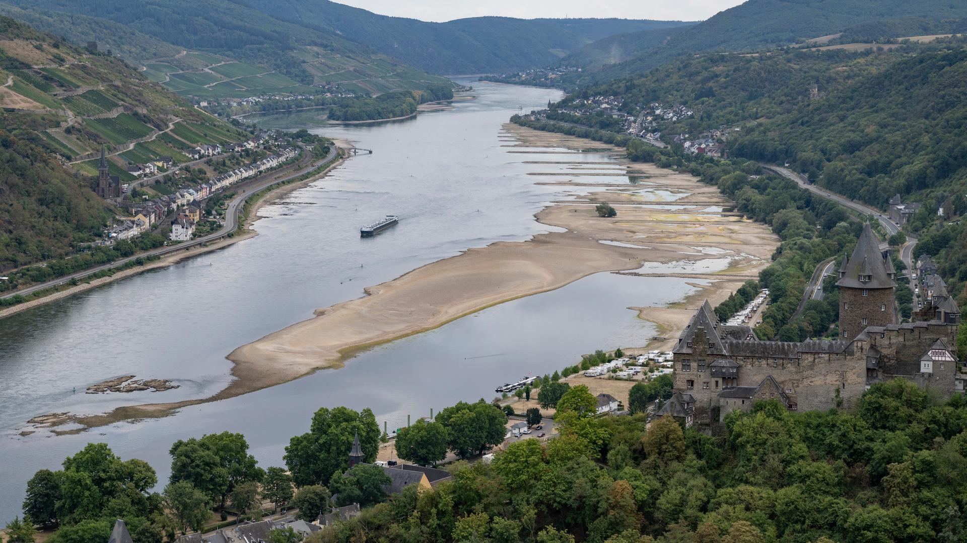 Ein Binnenschiff fährt bei Niedrigwasser an freiliegenden Felsen und Sandbänken auf dem Rhein. Die Pegelstände des Rheins haben nach wochenlanger Trockenheit teils historische Tiefststände erreicht. Sinken die Pegel weiter, droht die Schifffahrt zum Erliegen zu kommen.