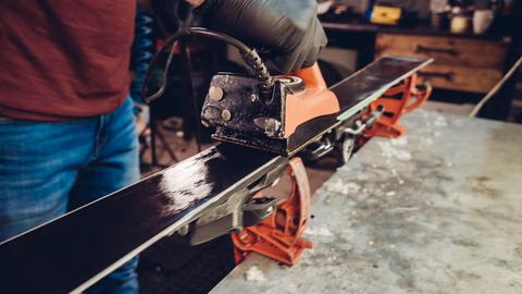 In einer Werkstatt wird Wachs auf einen Ski aufgetragen.