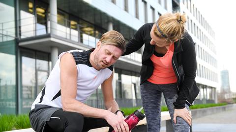 Gestellte Szene: Ein Mann macht eine Pause vom Joggen und seine Freundin schaut, wie es ihm geht.