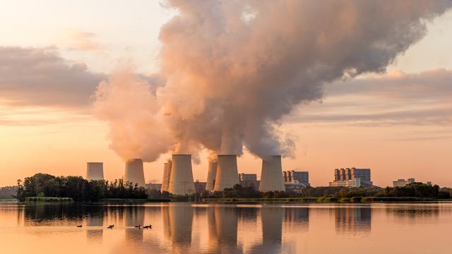 Das Kraft-Werk Jänschwalde. Aus den Kühl-Türmen steigt Wasser-Dampf auf. Der Dampf spiegelt sich im Wasser davor.