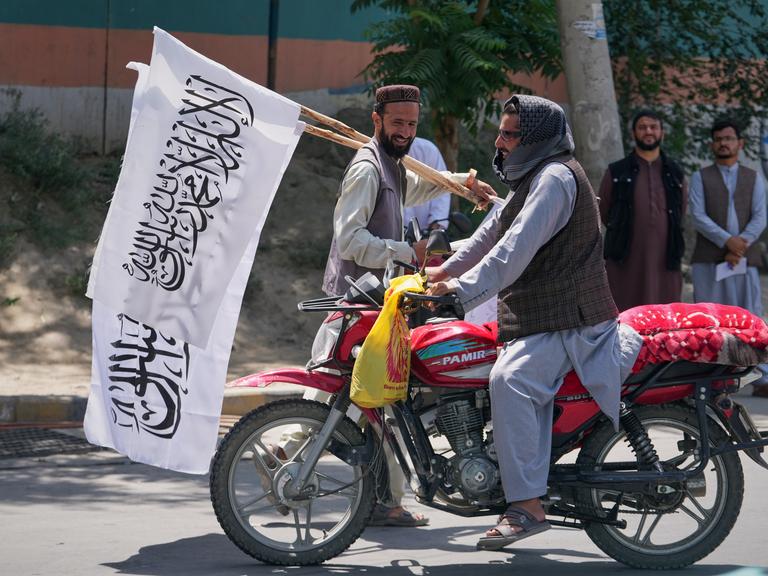 Ein Mann bietet Taliban-Flaggen zum Verkauf in Kabul an. Ein Mann bietet Taliban-Flaggen zum Verkauf in Kabul an.