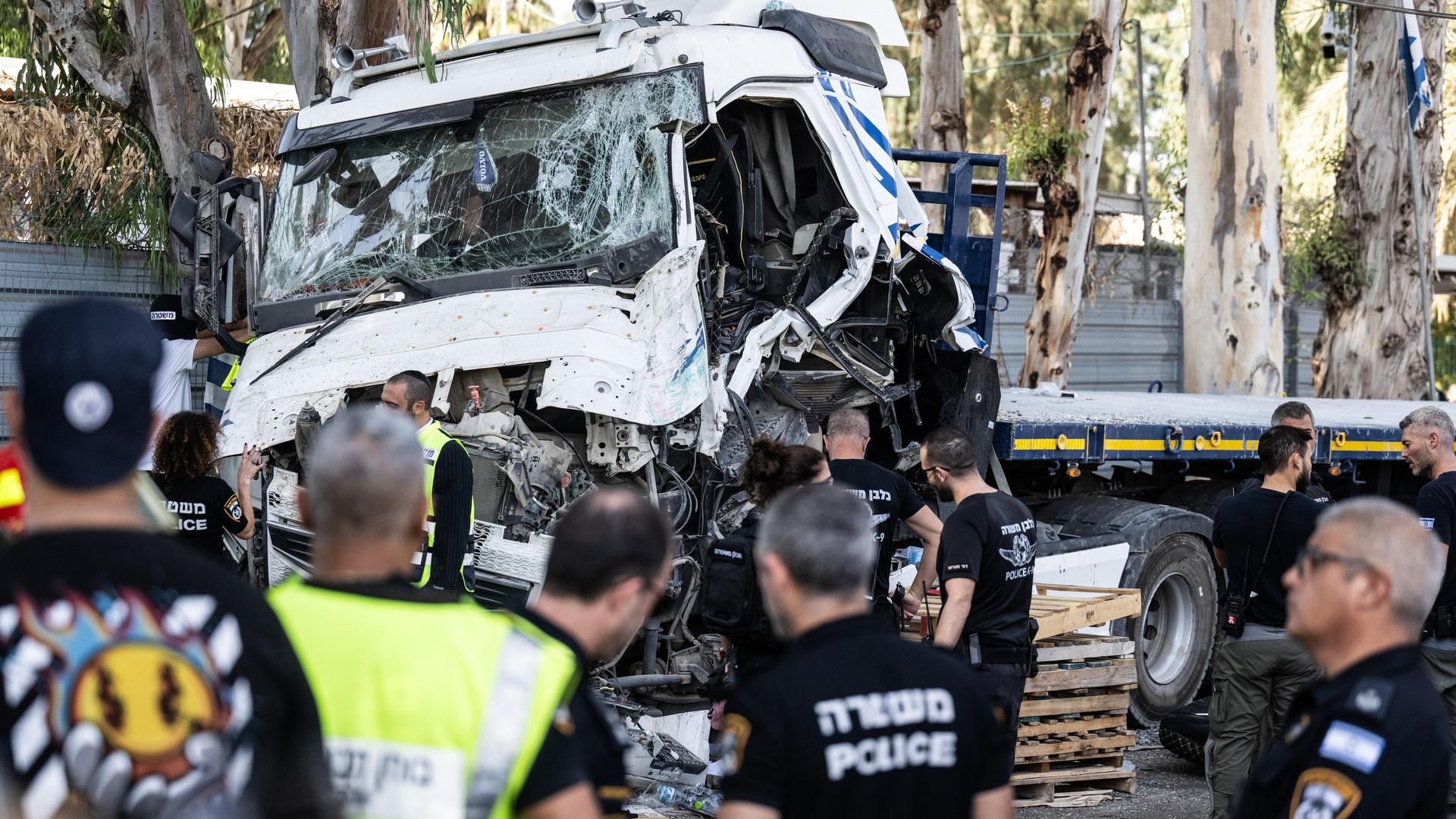 Rettungskräfte versorgen Verletzte vor einem LKW, dessen Führerhaus stark beschädigt ist.