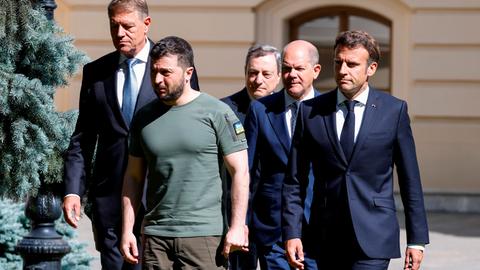 Frankreichs Präsident Emmanuel Macron, der rumänische Präsident Klaus Johannis, Italiens Premierminister Mario Draghi und Bundeskanzler Olaf Scholz, alle in Anzug, stehen mit Präsident Wolodimir Selenski, in Militärkleidung, zusammen.