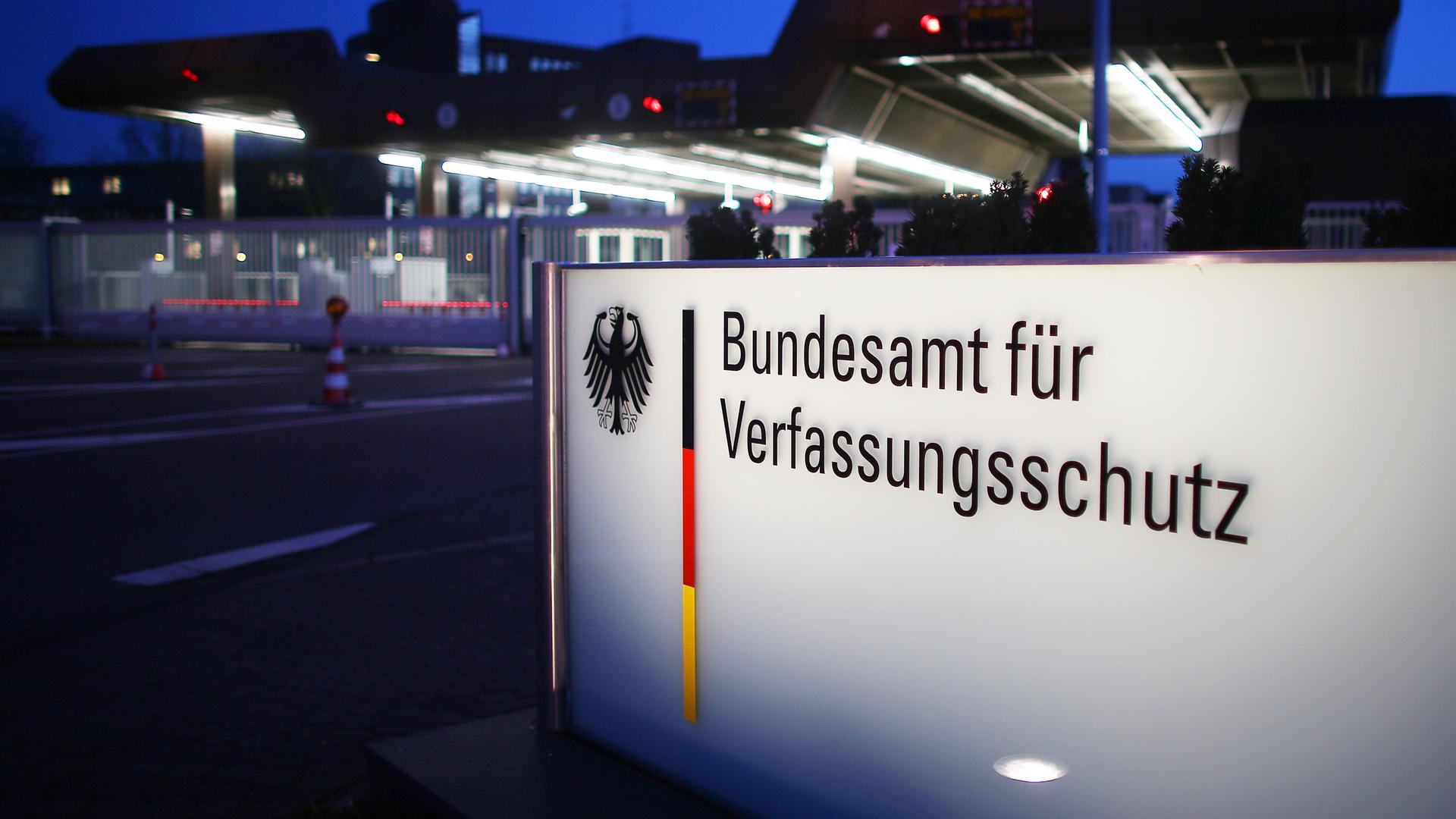 Nachtaufnahme eines beleuchteten Schildes mit der Aufschrift "Bundesamt für Verfassungsschutz" 