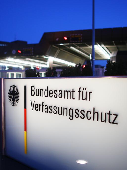 Nachtaufnahme eines beleuchteten Schildes mit der Aufschrift "Bundesamt für Verfassungsschutz" 