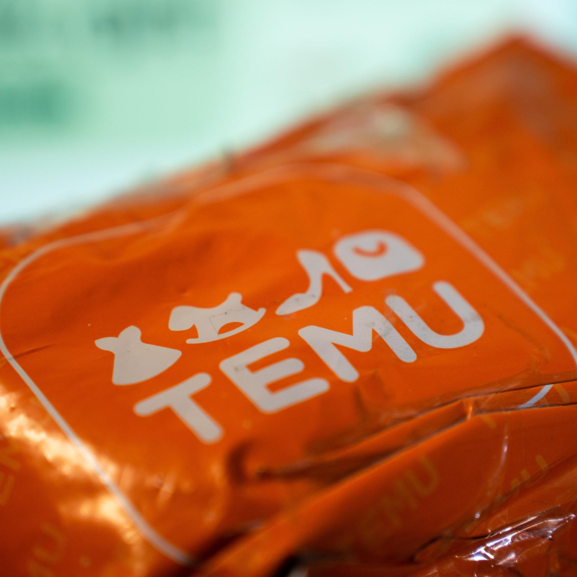 Das Bild zeigt ein orangenes Paket mit der Aufschrift "Temu". (Photo by Nikos Pekiaridis/NurPhoto)
