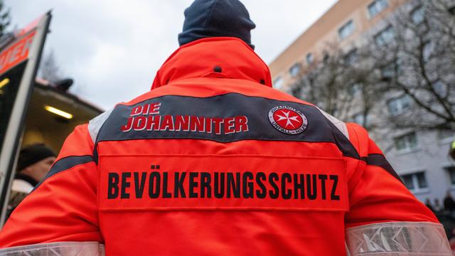 Ein Mann mit roter Jacke, auf deren Rückseite die Aufschrift "Die Johanniter - Bevölkerungsschutz" zu lesen ist Ein Mann mit roter Jacke, auf deren Rückseite die Aufschrift "Die Johanniter - Bevölkerungsschutz" zu lesen ist