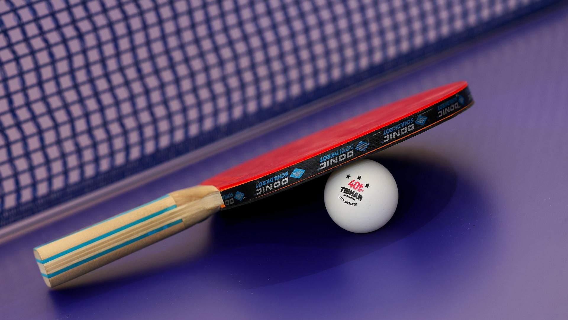 Ein Tischtennisschläger liegt auf einem Ball.