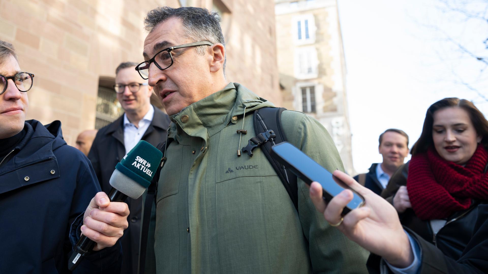 Cem Özdemir, Spitzenkandidat der Grünen in Baden-Württemberg, ist umringt von Journalisten und spricht in ein SWR-Mikrofon.