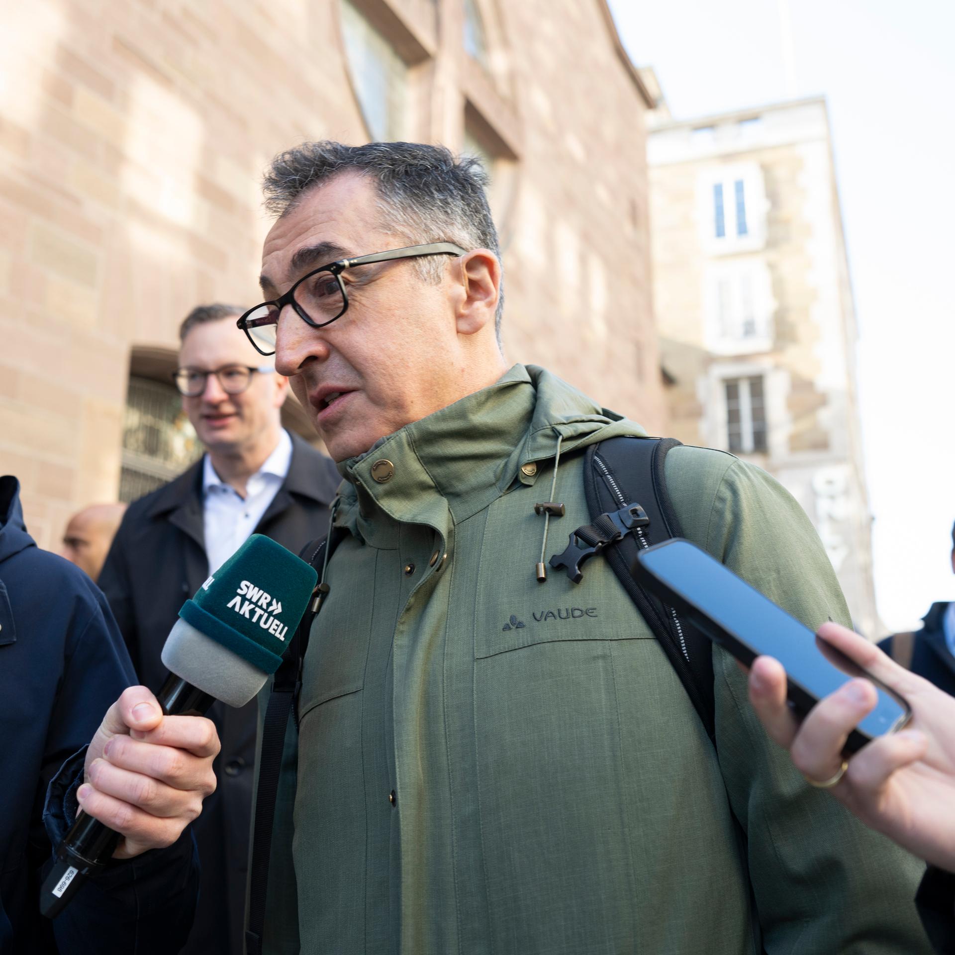 Cem Özdemir, Spitzenkandidat der Grünen in Baden-Württemberg, ist umringt von Journalisten und spricht in ein SWR-Mikrofon.