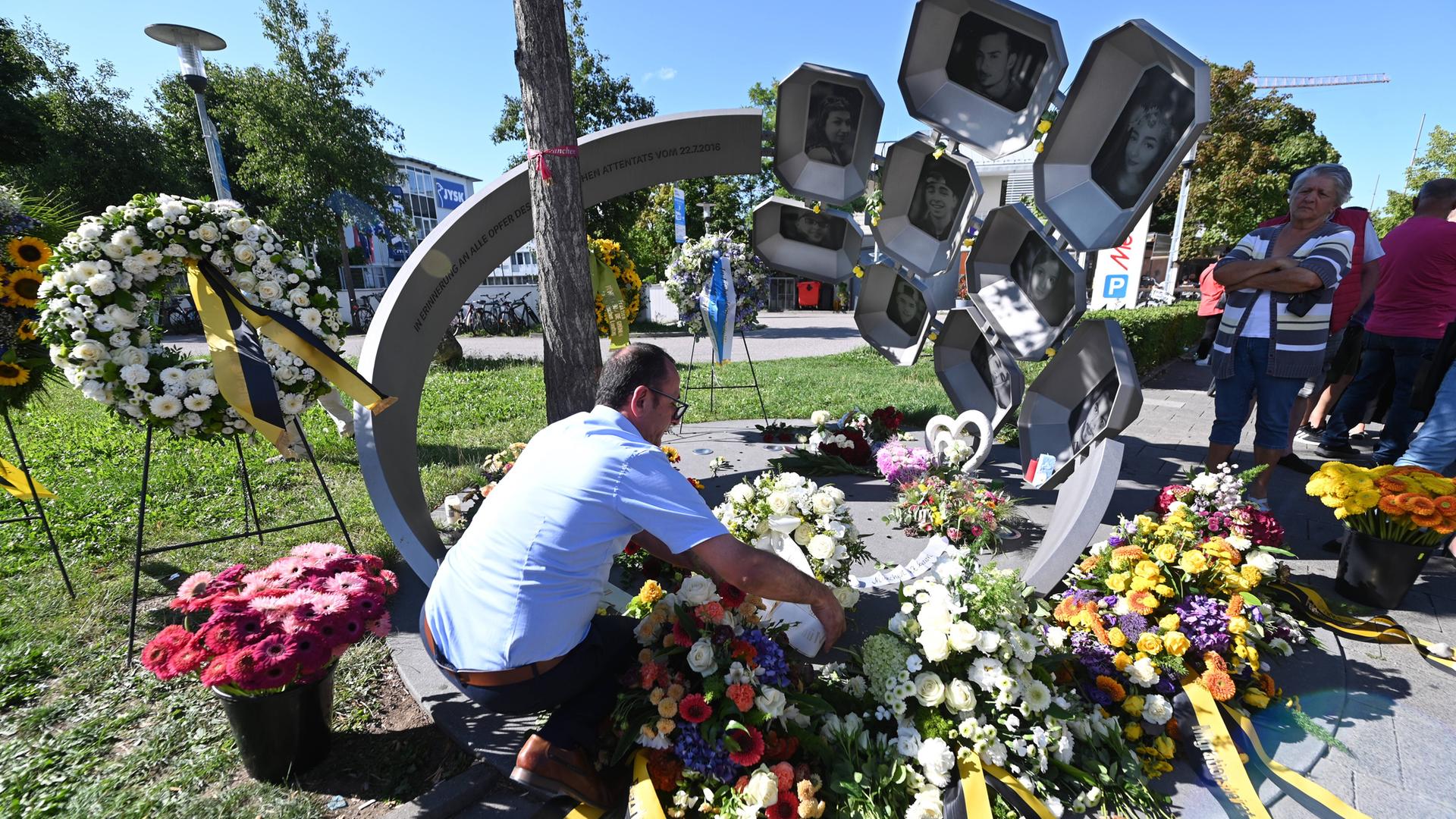 Bei einer Gedenkveranstaltung zum neunten Jahrestag des rechtsextremen Anschlags am Olympia-Einkaufszentrum (OEZ) 2016 in München legen Angehörige und Trauernde Blumen und Kränze am Denkmal vor dem OEZ nieder. Bei einer Gedenkveranstaltung zum neunten Jahrestag des rechtsextremen Anschlags am Olympia-Einkaufszentrum (OEZ) 2016 in München legen Angehörige und Trauernde Blumen und Kränze am Denkmal vor dem OEZ nieder.