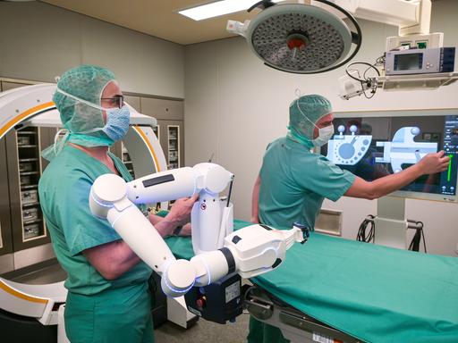 Zwei Ärzte verfolgen auf dem Bildschirm die OP, welche durch einen Roboter unterstützt wird.