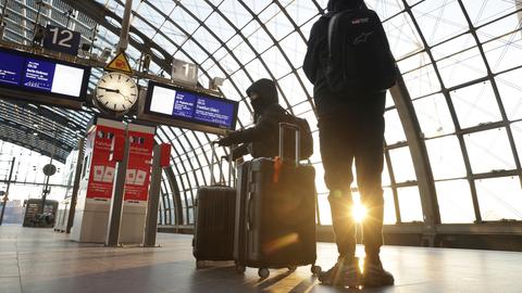 Menschen mit Koffern warten auf einem Bahnsteig am Hauptbahnhof in Berlin, Deutschland.