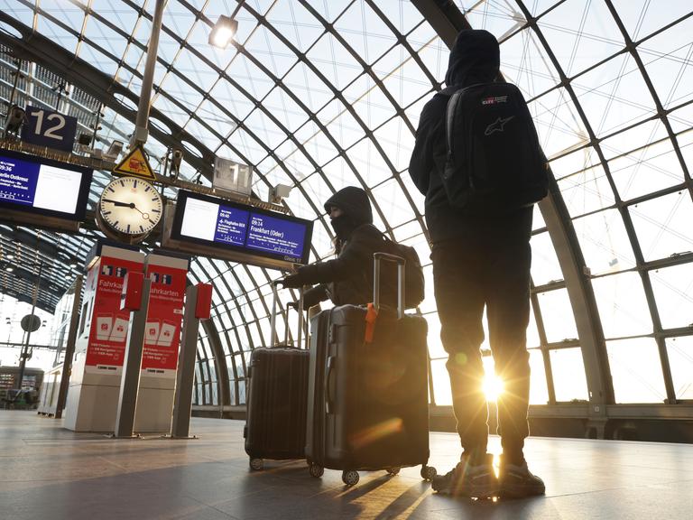 Menschen mit Koffern warten auf einem Bahnsteig am Hauptbahnhof in Berlin, Deutschland.