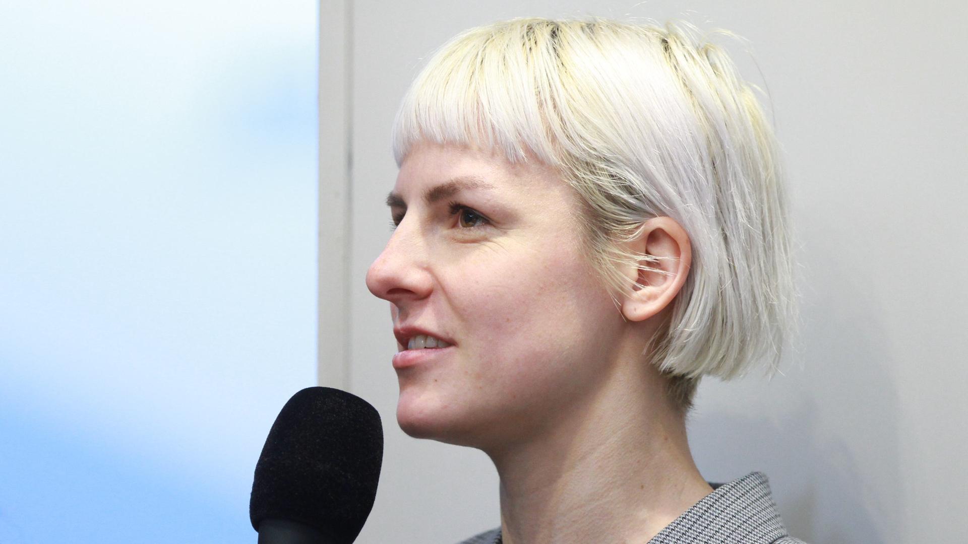 Die Schriftstellerin Helene Bukowski im Profil mit einem Mikrofon in der Hand.