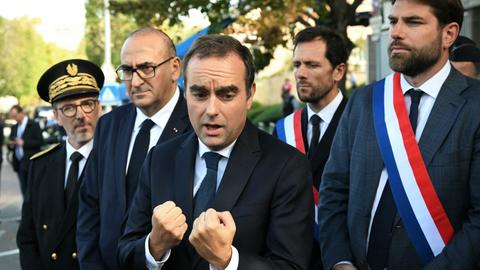 Der französische Premierminister Sébastien Lecornu ballt die Fäuste. An seiner Seite stehen mehrere Abgeordneten nach einem Besuch einer Polizeistation bei Paris.