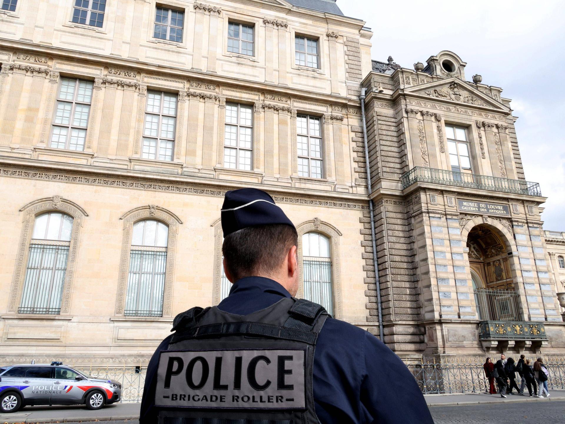 Vor dem Louvre steht ein Polizist.