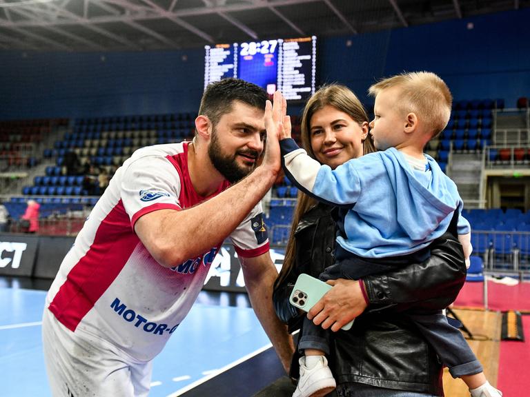 Ein Spieler des ukrainischen Meisters HK Motor Saporischschja klatscht mit einem Kind ab. 