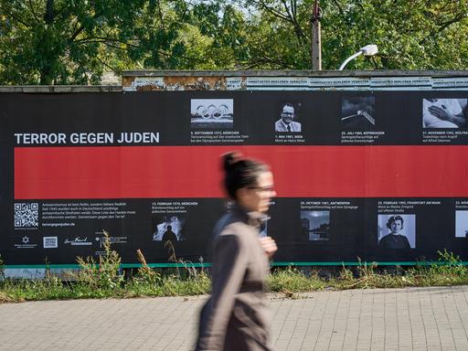 Eine Frau geht an einem Plakat mit der Aufschrift "Terror gegen Juden" vorbei.