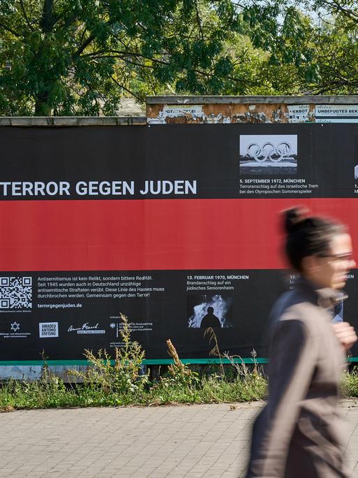 Eine Frau geht an einem Plakat mit der Aufschrift "Terror gegen Juden" vorbei.