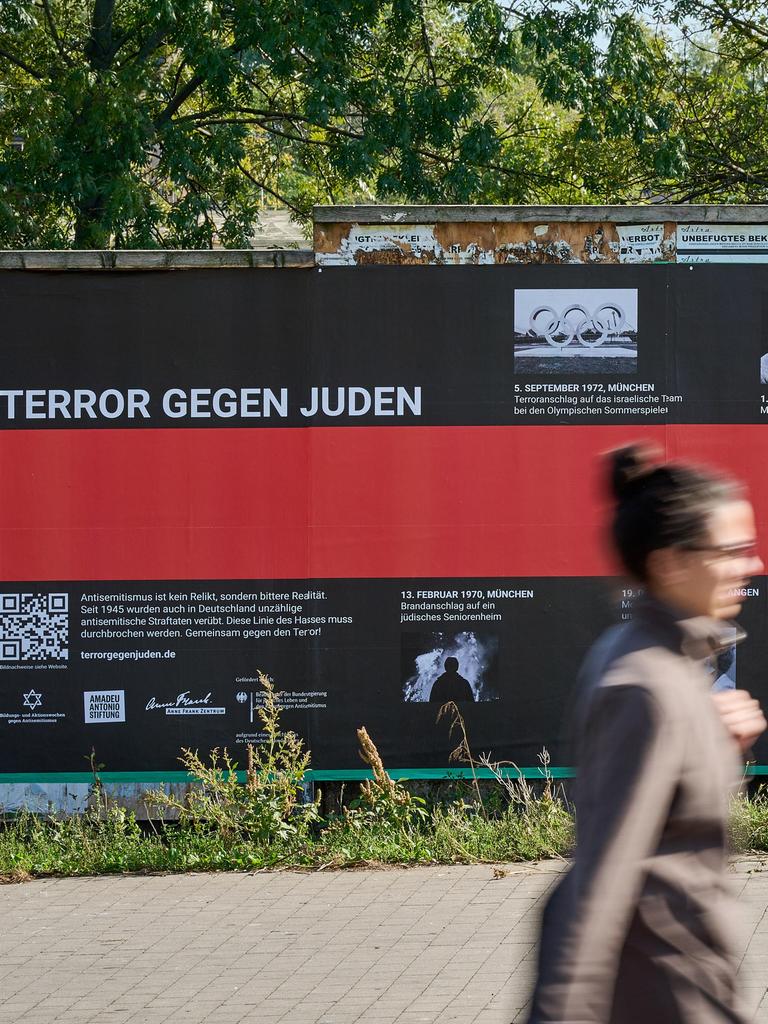 Eine Frau geht an einem Plakat mit der Aufschrift "Terror gegen Juden" vorbei.
