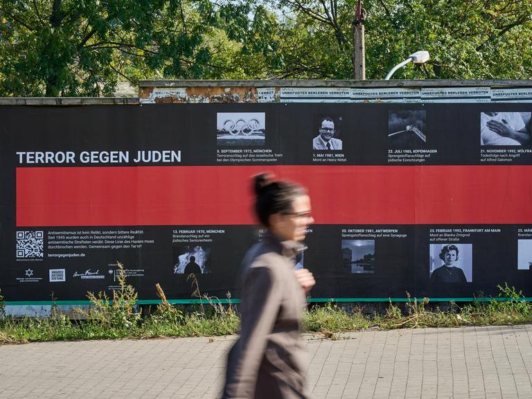 Eine Frau geht an einem Plakat mit der Aufschrift "Terror gegen Juden" vorbei.