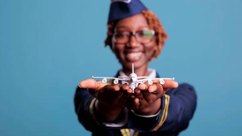 Eine witzige Stewardess hält der Betrachterin einen Mini-Modellflieger entgegen. Eine witzige Stewardess hält der Betrachterin einen Mini-Modellflieger entgegen.