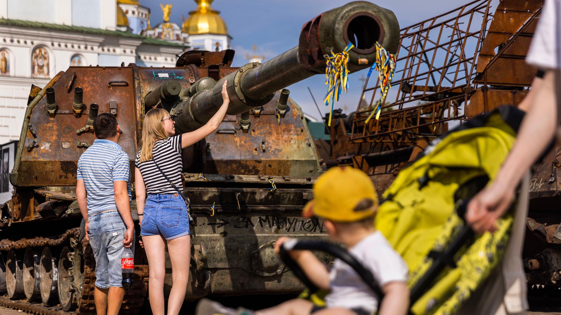 Menschen begutachten zerstörte russische Panzer in Kiew.