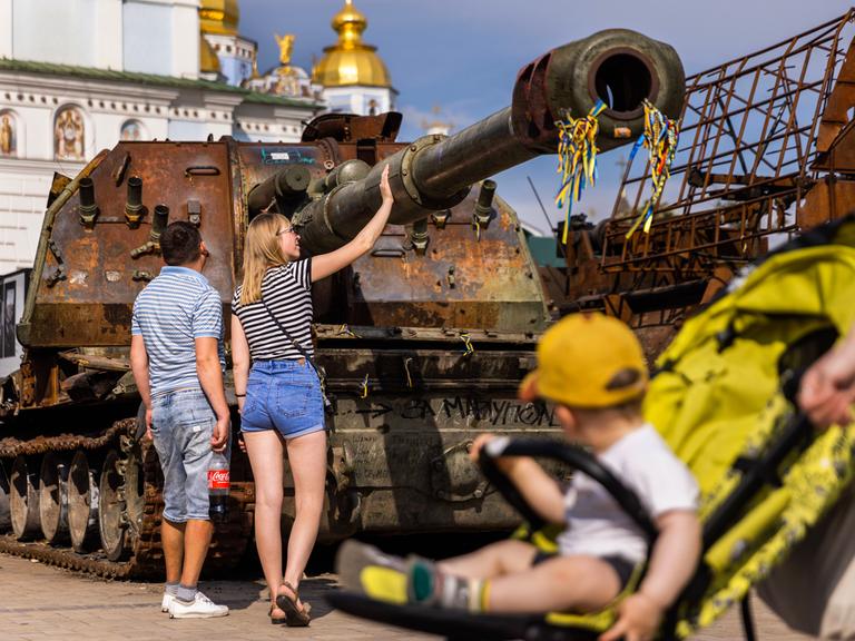 Menschen begutachten zerstörte russische Panzer in Kiew.