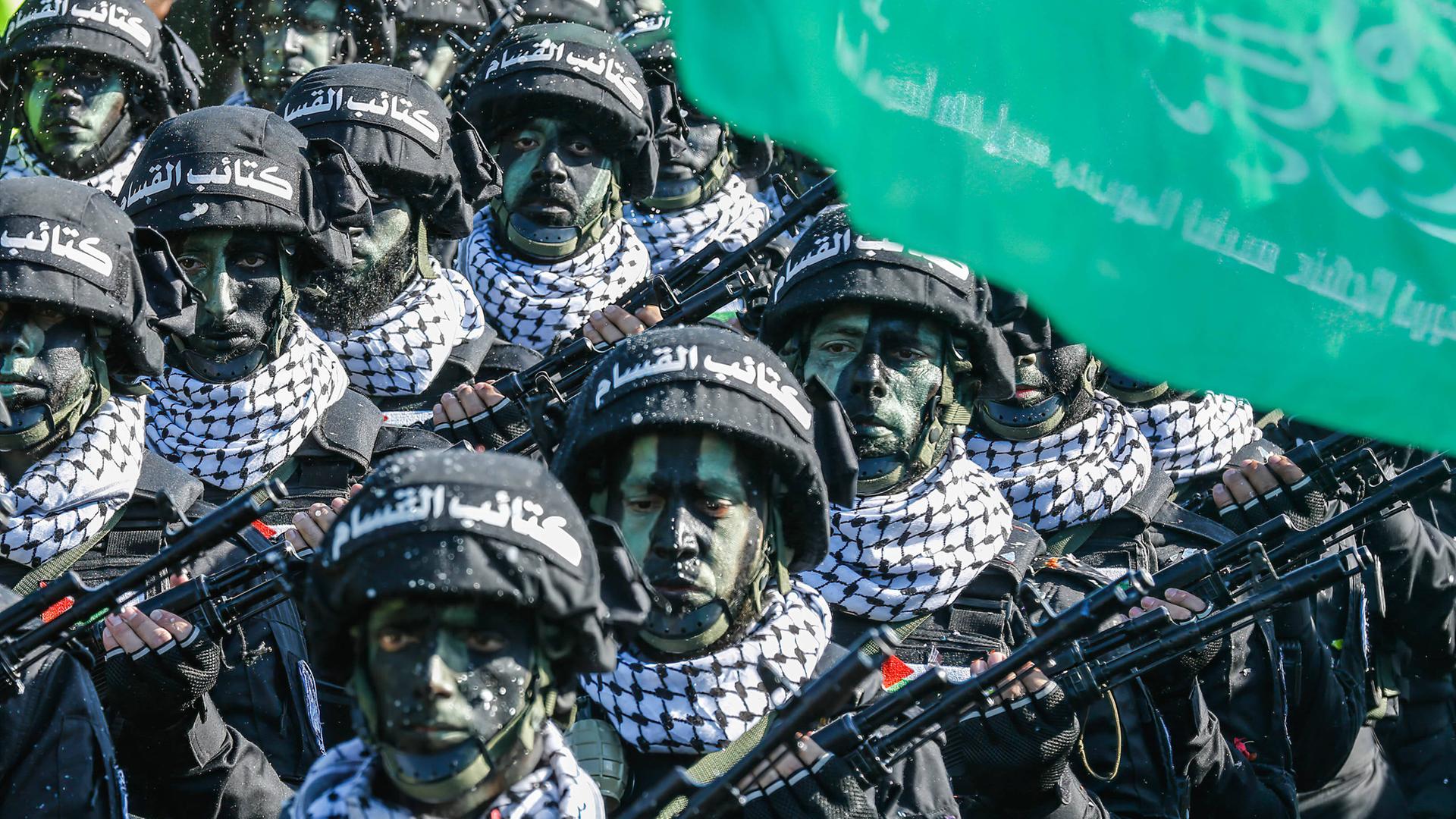 Archivbild: Kämpfer der Hamas stehen bei einer Parade geschminkt und mit Helm in einer Reihe.