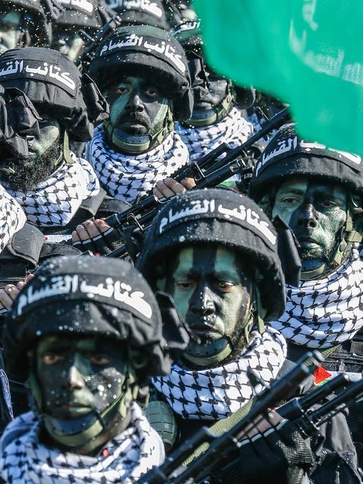 Archivbild: Kämpfer der Hamas stehen bei einer Parade geschminkt und mit Helm in einer Reihe.