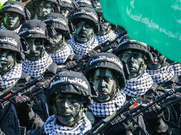 Archivbild: Kämpfer der Hamas stehen bei einer Parade geschminkt und mit Helm in einer Reihe.