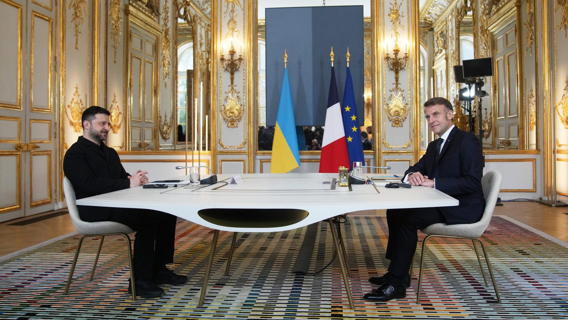 Emmanuel Macron und Wolodymyr Selenskyj sitzen im Elysee-Palast an einem Tisch sich gegenüber. Emmanuel Macron und Wolodymyr Selenskyj sitzen im Elysee-Palast an einem Tisch sich gegenüber.