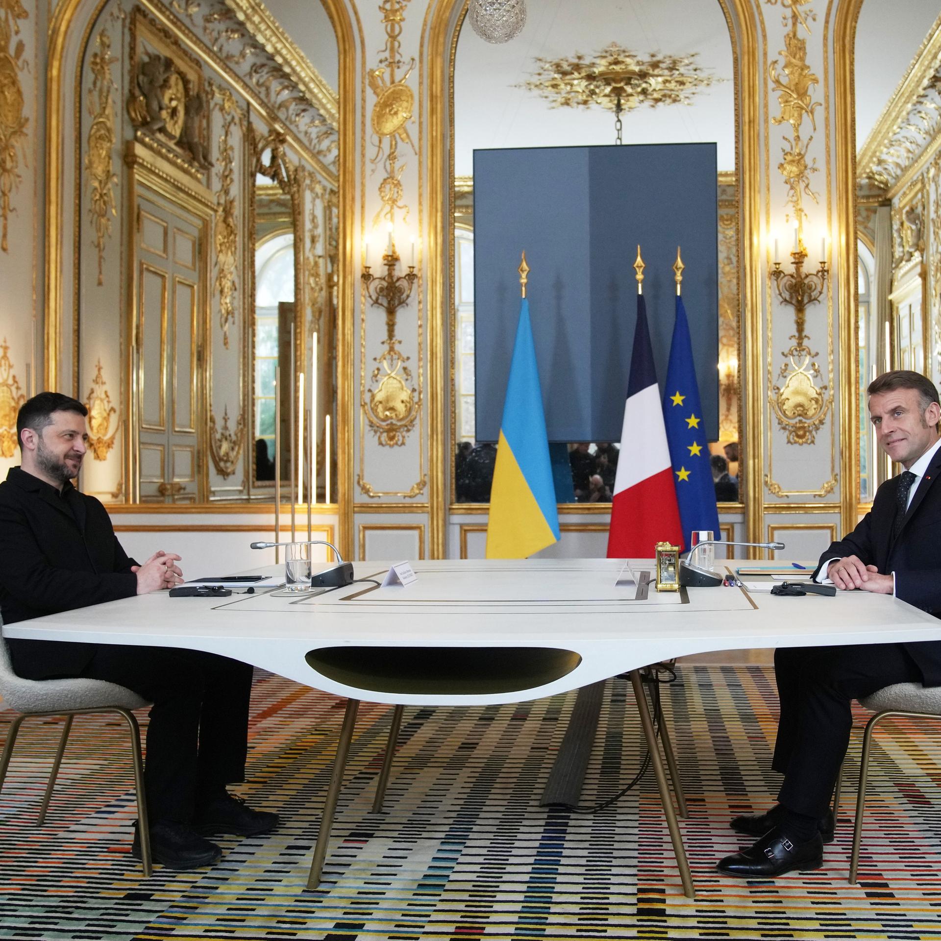 Emmanuel Macron und Wolodymyr Selenskyj sitzen im Elysee-Palast an einem Tisch sich gegenüber. 