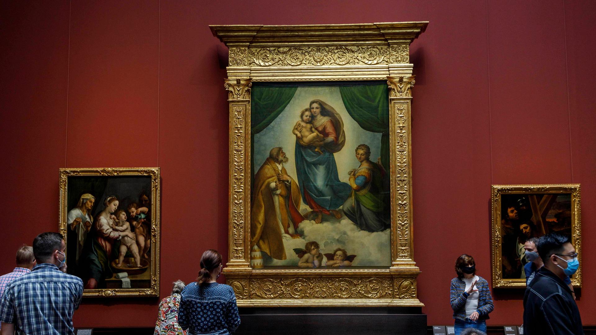 Museumsbesucher- und besucherinnen betrachten die Sixtinische Madonna von Raffael in der Gemäldegalerie Alte Meister in Dresden.