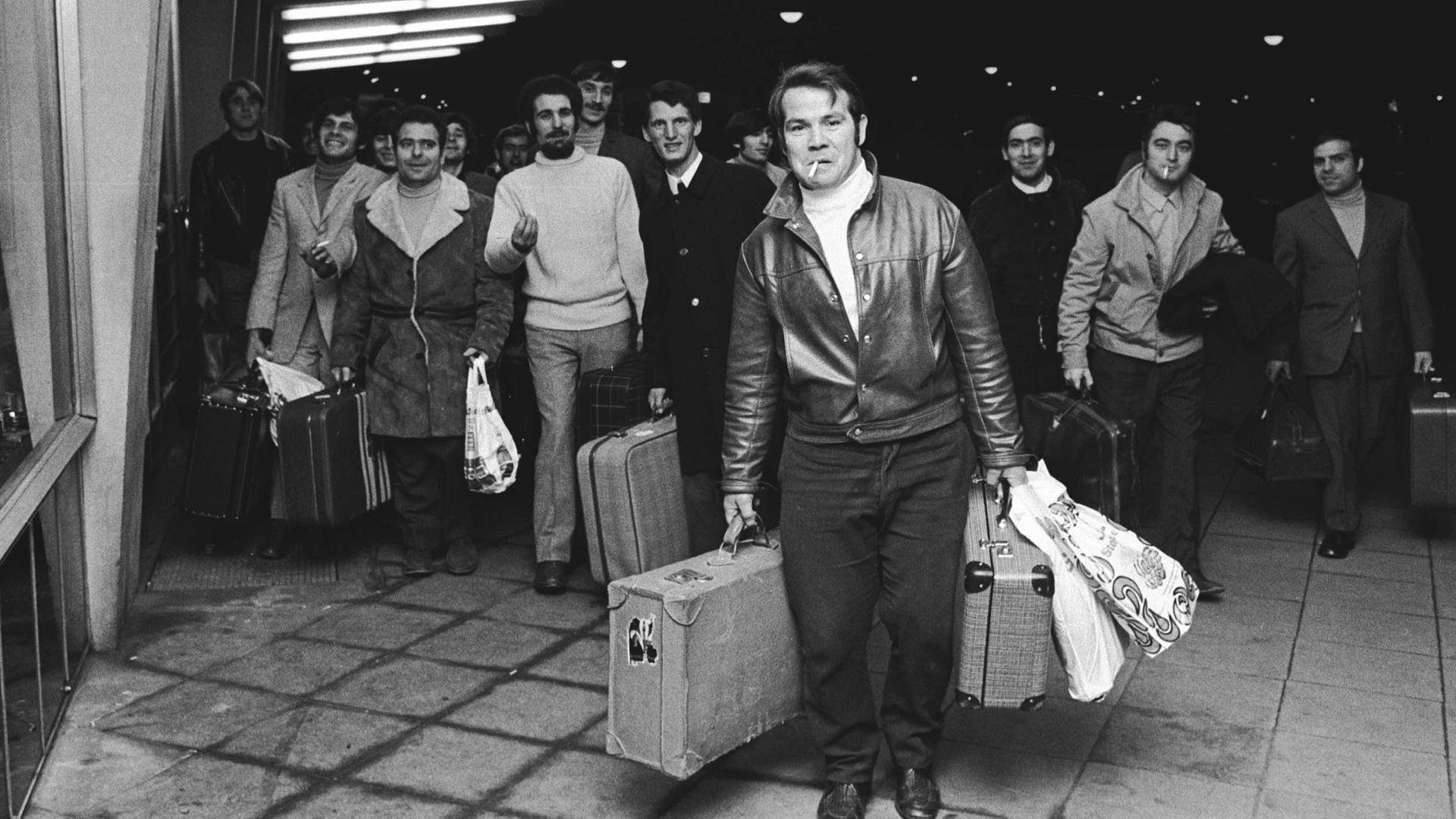 Fotografie aus dem Jahr 1970: Am Bahnhof in Wolfsburg laufen italienische VW-Gastarbeiter aus Italien mit Koffern und Taschen auf dem Bahnsteig entlang.