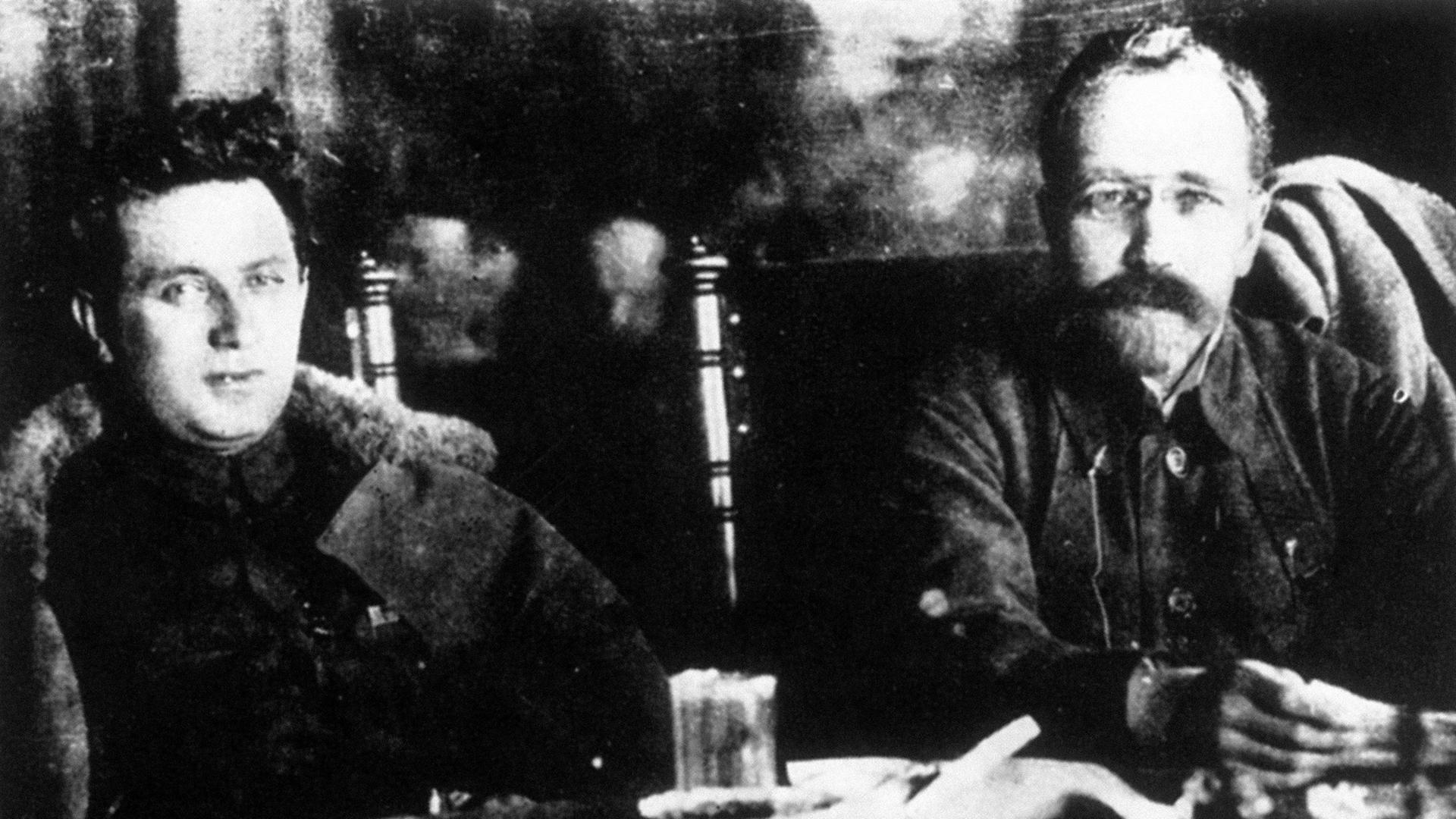 Grigori Sinowjew (li.) und Lew Kamenew sitzen hinter einem Tisch