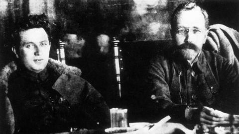 Grigori Sinowjew (li.) und Lew Kamenew sitzen hinter einem Tisch