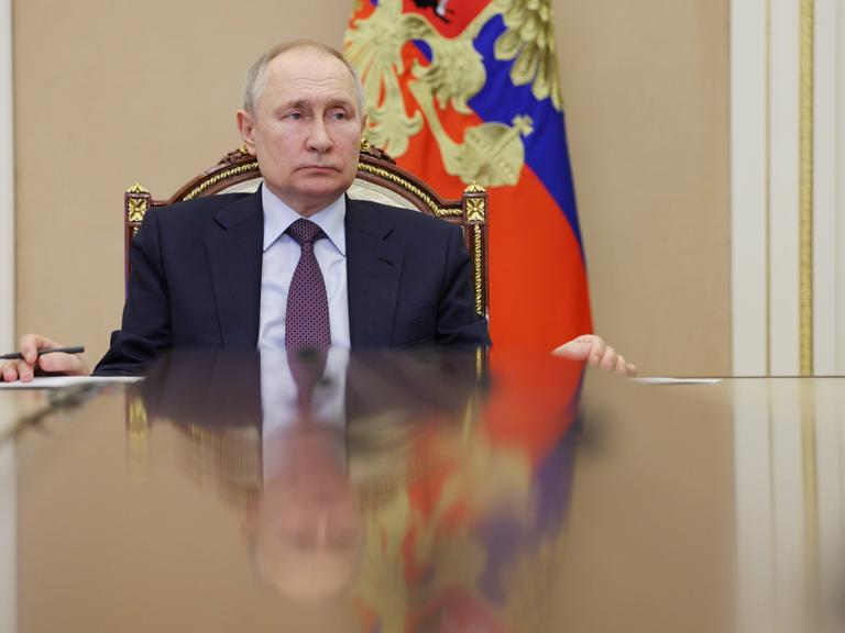 Russlands Präsident Wladimir Putin sitzt an einem Tisch. 
