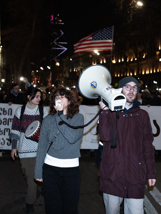 Proteste in Georgien: Personen mit Transparenten, europäischen und amerikanischen Flaggen ziehen durch die Straßen der georgischen Hauptstadt und demonstrieren gegen die georgische Regierung.