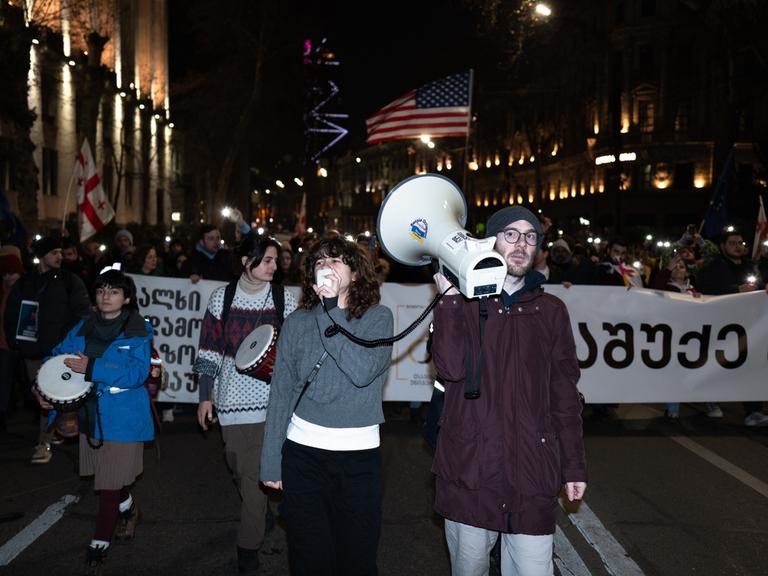 Proteste in Georgien: Personen mit Transparenten, europäischen und amerikanischen Flaggen ziehen durch die Straßen der georgischen Hauptstadt und demonstrieren gegen die georgische Regierung.