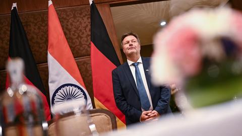 Robert Habeck steht wartend vor deutschen und indischen Nationalflaggen.
