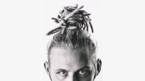 Foto eines weißen Mannes mit Dreadlocks. Er trägt sie als Dutt auf dem Kopf. Das Foto ist schwarzweiß und unter seinen Augen abgeschnitten. 